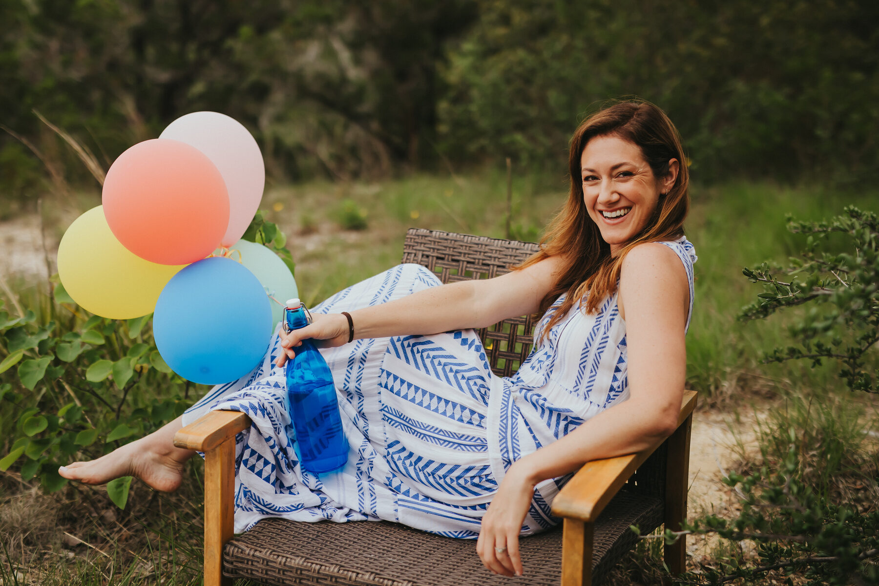 Amanda relaxing in a chair outdoors holding pastel balloons